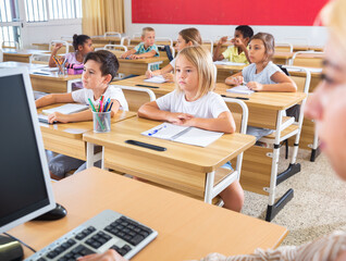 Fototapeta premium Pupils of primary school listening new theme and attentively watching video at class