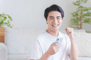 スマホを持ってガッツポーズする男性