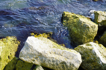 Ocean waves, crashing onto large rocks.