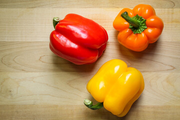 Colorful bell peppers on wooden cutting board