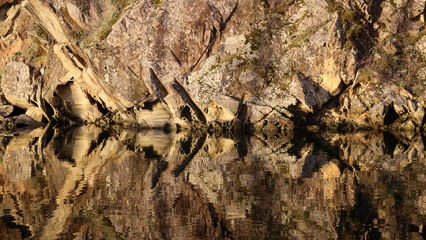 Rock formation reflected in ocean bay