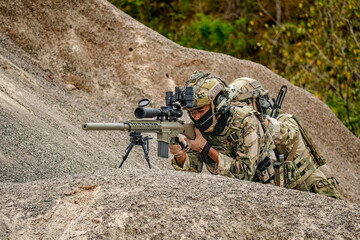 A group of military men in combat gear patrol in the middle of a desert and tropical jungle. Soldiers in full combat gear in dry weather conditions assemble and march on a mission.