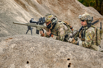 A group of military men in combat gear patrol in the middle of a desert and tropical jungle....