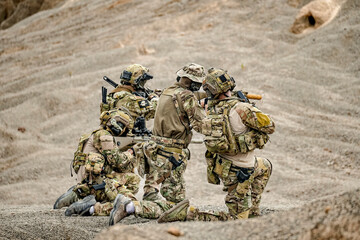 A group of military men in combat gear patrol in the middle of a desert and tropical jungle....