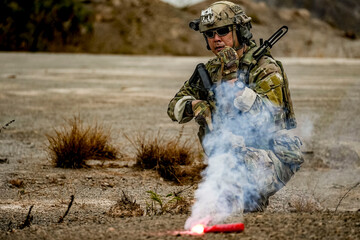 A group of military men in combat gear patrol in the middle of a desert and tropical jungle....