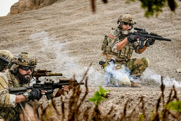 A group of military men in combat gear patrol in the middle of a desert and tropical jungle....