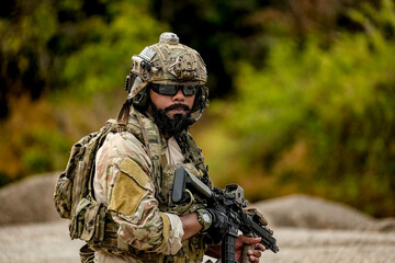 A group of military men in combat gear patrol in the middle of a desert and tropical jungle. Soldiers in full combat gear in dry weather conditions assemble and march on a mission.