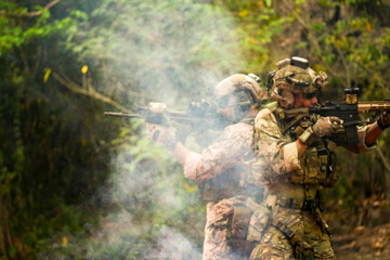 A group of military men in combat gear patrol in the middle of a desert and tropical jungle....