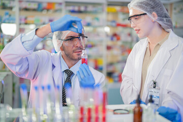 scientists perform experiments and record data. people arranges equipment with test tubes and chemicals for producing medicine and biochemistry. man hold tubes of chemical liquids and plant samples.