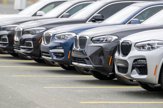 St. John's, Newfoundland - July 6, 2024: A row of blue, black, and grey BMW X5 M60i EUV utility vehicles are in a car dealership parking lot. The new vehicles are electric rechargeable automobiles.