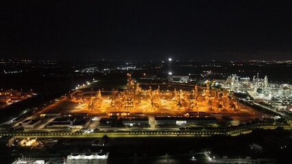 High angle view of industrial plant with pipes and tanks for mixing chemicals and gases at night.