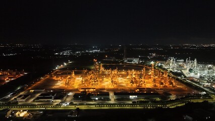High angle view of industrial plant with pipes and tanks for mixing chemicals and gases at night.