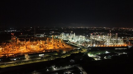 High angle view of industrial plant with pipes and tanks for mixing chemicals and gases at night.