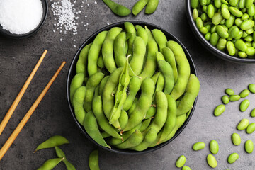 Raw green edamame soybeans and pods on grey table, flat lay