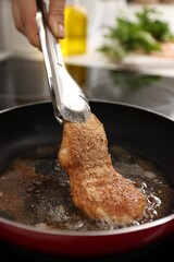 Woman cooking schnitzel in frying pan on stove, closeup