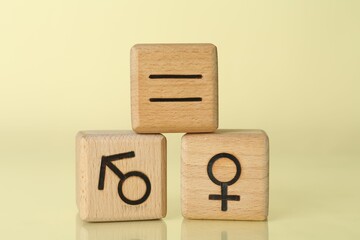 Gender equality concept. Wooden cubes with male and female symbols on light yellow background