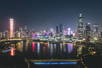 Naklejka premium Stunning Nighttime City Skyline with Reflective Lake and Colorful Lights