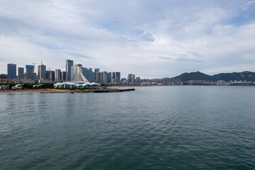 Fototapeta premium Serene Waterfront Cityscape with Modern Skyline and Mountains