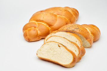 Sliced challah bread with sesame and poppy seeds on a white background