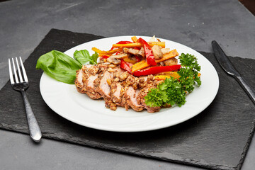 Tender sliced meat with roasted vegetables and fresh herbs on a white plate