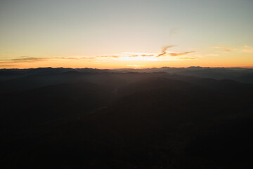Aerial view of dark mountain hills at sunset. Hazy peaks and misty valleys in evening