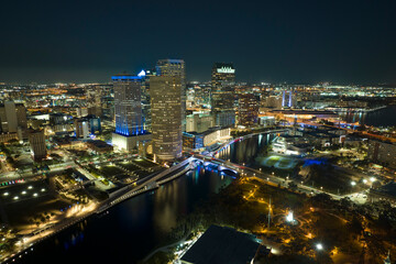Fototapeta premium Aerial view of downtown district of Tampa city in Florida, USA. Brightly illuminated high skyscraper buildings, pedestrian riverwalk and moving traffic in modern american midtown