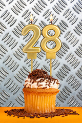 Chocolate cupcake with candle number 28 - Birthday on industrial metallic background.