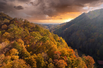 Appalachian mountain hills on autumn evening with brightly illuminated lush and pine woods at fall...