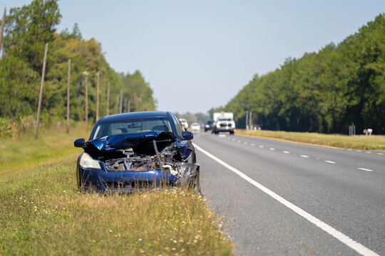 Crashed car damaged in traffic accident parked on road side. Abandoned broken vehicle