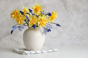 daffodils and hyacinths in a vase on the table. a light composition that conveys the feeling of...