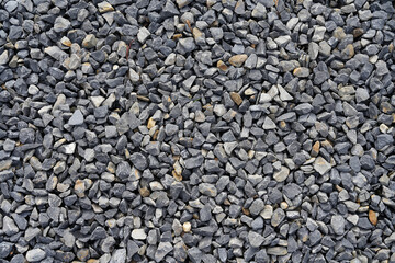 A close-up photograph showcasing a bed of small, grey stones arranged compactly together,...