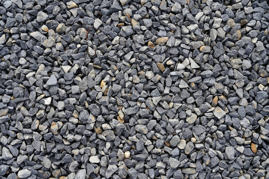 A close-up photograph showcasing a bed of small, grey stones arranged compactly together, emphasizing texture, pattern, and uniformity, suitable for various uses.