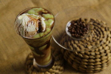 A creamy avocado juice topped with a scoop of ice cream, set against an aesthetic brown burlap background, rich and indulgent.