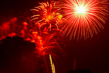 Red sky exploding with bright yellow fireworks and streaks of light filling the night during a...