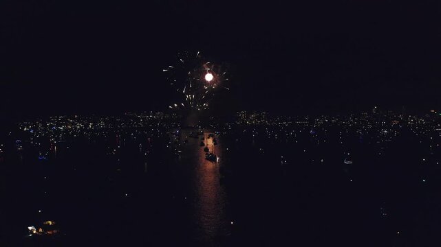 Drone, ships and fireworks for celebration at night in city, urban or development in Hong Kong. Ocean, dark and lights for New Years, festival or holiday in aerial view for traveling, trip and coast