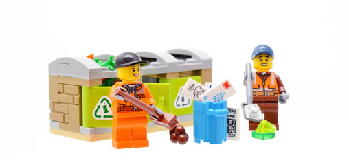 Fototapeta premium ego minifigures of cleaning service are removing a garbage of different materials isolated on white background. Editorial illustrative image of popular plastic toy.