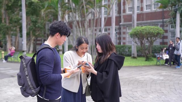 Young Taiwanese man and woman in their twenties chatting amiably with a South Asian woman in a slow-motion video on a university campus in Da&rsquo;an District, Taipei.