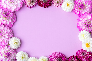 Pink, purple, burgundy frame of dahlia flowers on purple background with place for text in center. Floral Greeting card. Nature trendy decorative design. Nature concept. Flat lay.