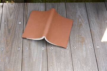屋外で木のベンチに置かれた一冊の本