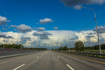 Fototapeta premium A long, empty highway with a few trees in the background