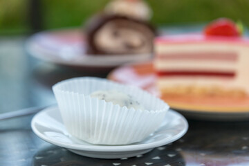 A white cupcake sits on a white plate on a table
