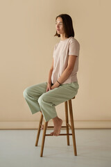 Full length image of a young confident woman in a casual clothes, short hairstyle sitting on a high...