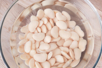 Soaking butter beans in water in a glass bowl. Vegan healthy diet food ingredients.