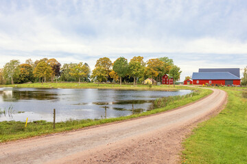 Farm house by a lake with a gravel road an autumn day