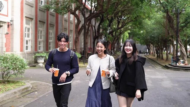 In Taipei's Da'an District, a slow-motion video captures a young Taiwanese man and woman with a South Asian woman, all in their twenties, walking and chatting amicably on a university campus.