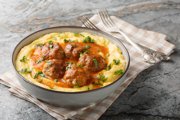 Baked corn porridge with meatballs and spicy gravy close-up in a bowl on the table. Horizontal