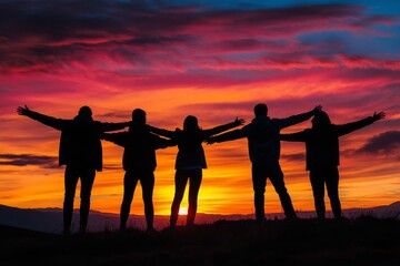 Fototapeta premium A group of friends standing in silhouette against the sky at sunset, arms outstretched, conveying a sense of friendship and togetherness.