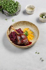 Gourmet Duck Confit with Red Cabbage and Orange Slices on Ceramic Plate