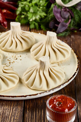 Fresh Khinkali on a Plate with Spices, Herbs, and Vegetables on Wooden Background