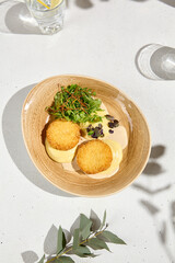 Mashed Potatoes with Fish Cakes and Bisque Sauce Garnished with Mixed Greens on Ceramic Plate